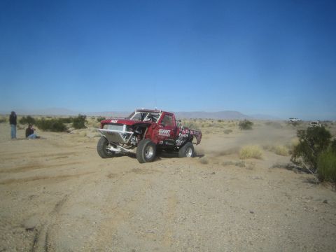 1990 Ford Bronco - Photograph of a red off-road race truck in the desert, not a technical document.
