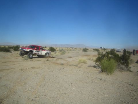 1990 Ford Bronco - Photograph of a red and white off-road race truck in the desert, not a technical document.