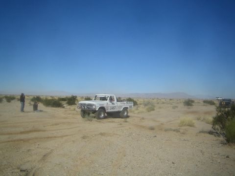 1990 Ford Bronco - Photograph of a white off-road race pickup in the desert, not a technical document.