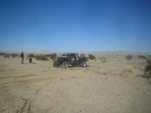 1990 Ford Bronco - Photograph of a black off-road race pickup in the desert, not a technical document.