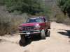 1996 Ford Bronco - This red Ford F-Series pickup truck, likely from the early to mid-1990s, navigates a dusty, off-road trail.