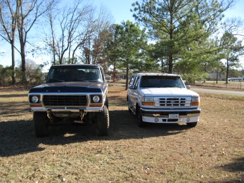 1978 Ford Bronco - Photograph of a vintage Bronco and a white Ford dually pickup in a yard, not a technical document.
