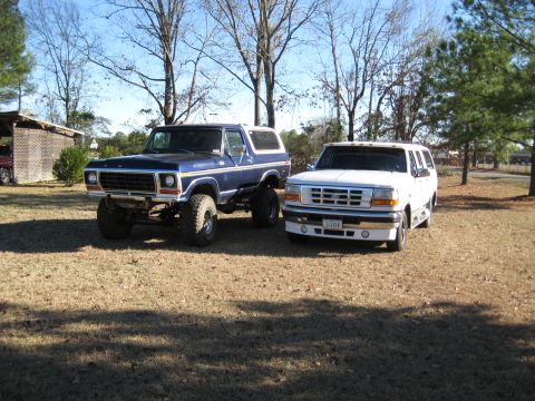 1978 Ford Bronco - Photograph of a lifted vintage Bronco and a white Ford crew-cab pickup, not a technical document.