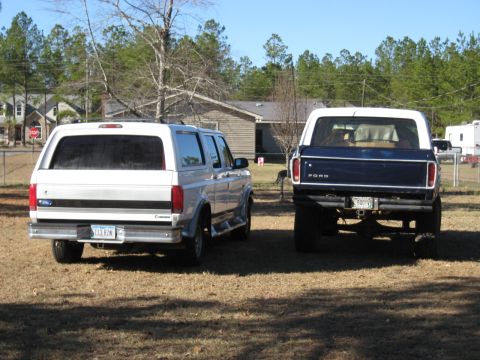 1978 Ford Bronco - Rear-end photograph of a silver Ford crew cab and a blue Ford pickup, not a technical document.
