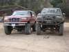 1996 Ford Bronco - Very small, low-resolution thumbnail showing two lifted full-size 4x4s parked side by side on a dirt trail, a red truck or SUV at left and…