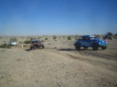 1990 Ford Bronco - Photograph of a blue Baja Bug, a small buggy and a white Bug racing across a rutted sandy desert section.