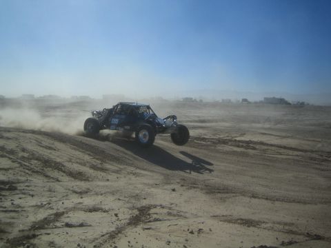 1990 Ford Bronco - Photograph of a tube-frame off-road race buggy racing through a dusty desert section.