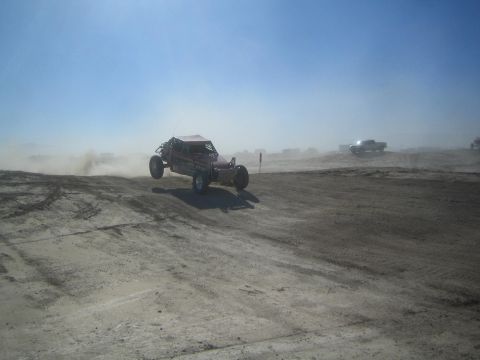 1990 Ford Bronco - Action photo of an off-road buggy kicking up dust on a desert course, not a technical document.