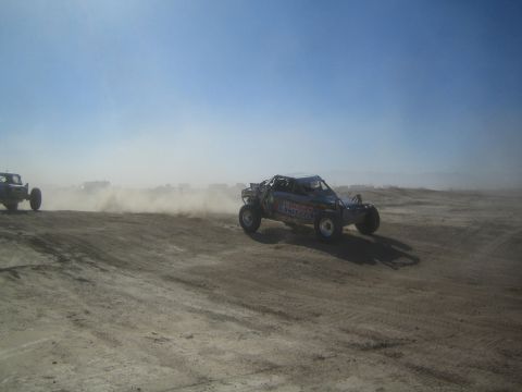1990 Ford Bronco - Action photo of an off-road buggy at speed on a desert course, not a technical document.