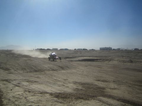 1990 Ford Bronco - Action photo of an off-road buggy racing across an open desert flat, not a technical document.