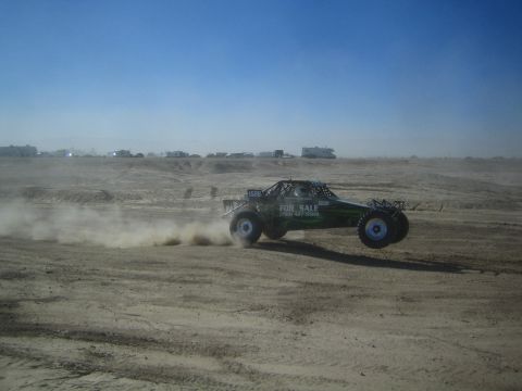 1990 Ford Bronco - Action photo of an off-road buggy with a FOR SALE decal at speed on a desert flat, not a technical document.