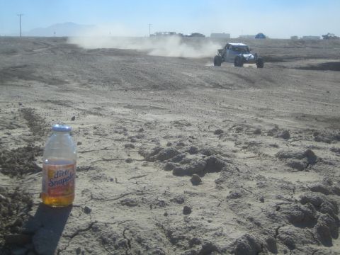 1990 Ford Bronco - Action photo of an off-road buggy in the desert with a drink bottle in the foreground, not a technical document.
