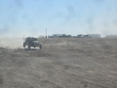 1990 Ford Bronco - Action photo of an off-road buggy jumping a rise on a desert course, not a technical document.