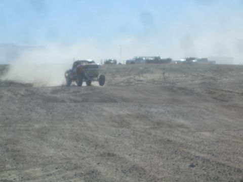1990 Ford Bronco - Action photo of an off-road truck at speed in heavy dust, not a technical document.