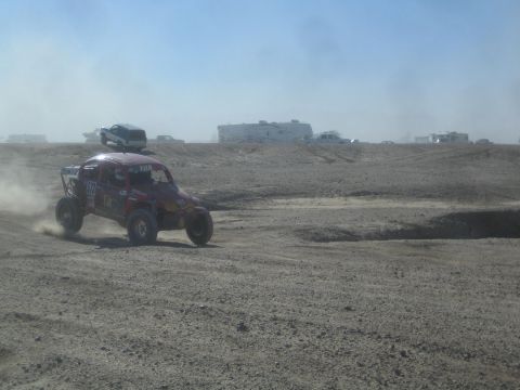 1990 Ford Bronco - Action photo of a purple off-road buggy on a desert course near spectator RVs, not a technical document.