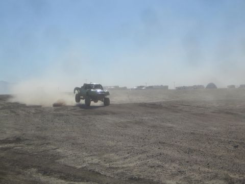 1990 Ford Bronco - Action photo of a green off-road truck catching air on a desert course, not a technical document.