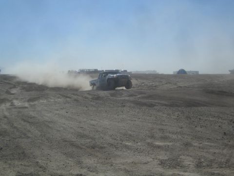 1990 Ford Bronco - Action photo of a silver off-road truck sliding on a desert course, not a technical document.