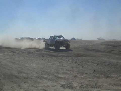 1990 Ford Bronco - Action photo of a white off-road truck at speed in the desert, not a technical document.