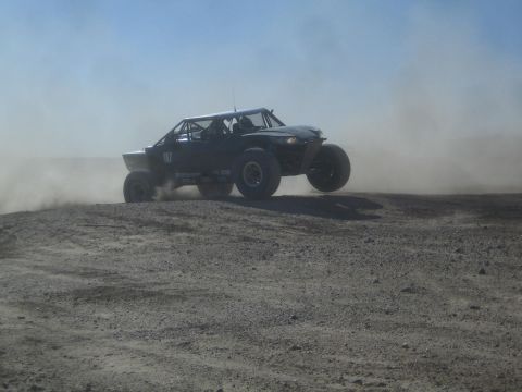 1990 Ford Bronco - Photograph of a black off-road race buggy on a dusty desert course, not a technical document.