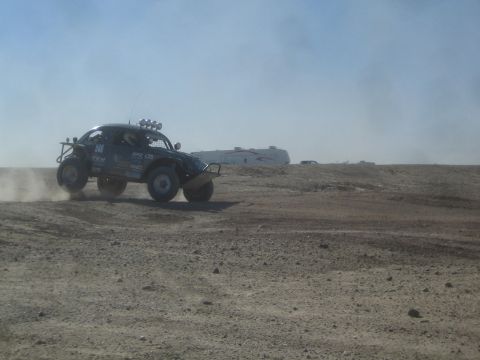 1990 Ford Bronco - Photograph of a blue off-road race buggy on a dusty desert course, not a technical document.