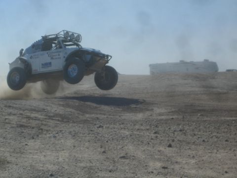 1990 Ford Bronco - Photograph of a white off-road race buggy jumping in a dusty desert, not a technical document.