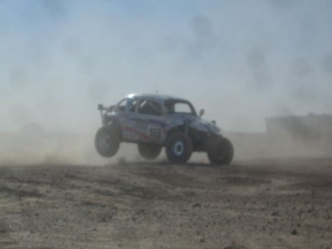 1990 Ford Bronco - Photograph of a white Baja Bug off-road racer on a dusty desert course, not a technical document.