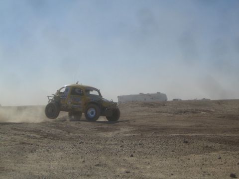 1990 Ford Bronco - Photograph of a yellow Baja Bug off-road racer on a dusty desert course, not a technical document.