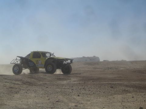 1990 Ford Bronco - Photograph of a yellow off-road race buggy on a dusty desert course, not a technical document.