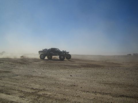 1990 Ford Bronco - Photograph of a black off-road race truck on an open dusty desert course, not a technical document.