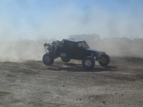 1990 Ford Bronco - Photograph of a black off-road race buggy on a dusty desert course, not a technical document.