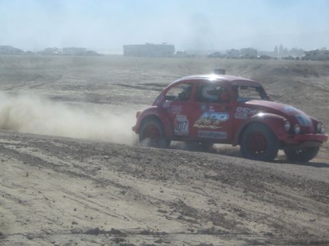 1990 Ford Bronco - Action photo of a red APP Racing Baja Bug number 207 racing through dust, not a technical document.