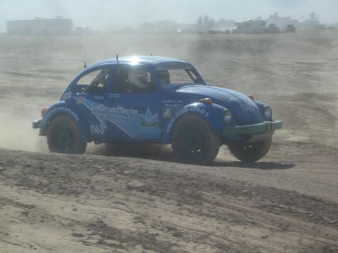 1990 Ford Bronco - Action photo of a blue Baja Bug number 1148 racing across a dusty desert track, not a technical document.