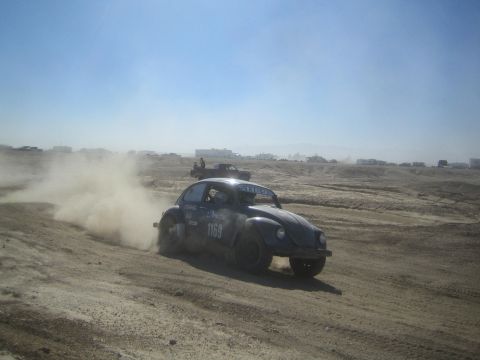 1990 Ford Bronco - Action photo of a Baja Bug number 1169 racing through dust on a desert course, not a technical document.