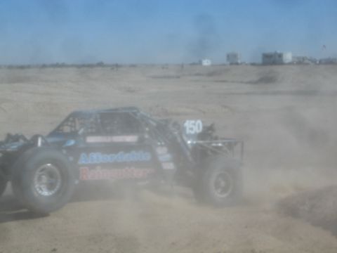 1990 Ford Bronco - Action photo of a black Affordable Raingutter off-road buggy number 150 racing through dust, not a technical document.