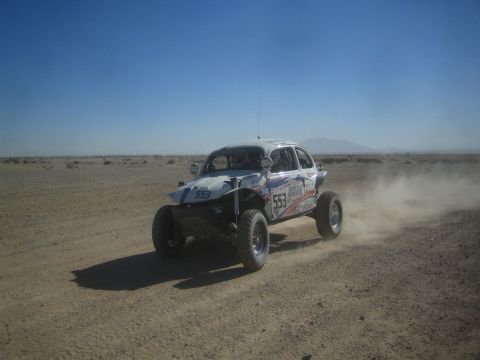 1990 Ford Bronco - Action photo of a white Baja Bug (number 553) racing through the desert; not a technical document.