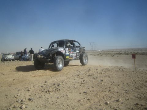 1990 Ford Bronco - Photograph of a black VW-based Baja Bug race car driving on a desert race course with spectators.
