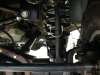 1996 Ford Bronco - Close-up underbody view of a coil-spring front suspension, showing a shock absorber/coil spring assembly mounted to control arms with surro…