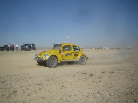 1990 Ford Bronco - Photograph of a yellow Volkswagen Baja Bug off-road race car kicking up dust on a desert course.