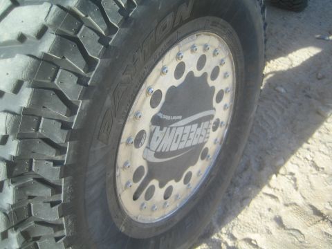 1990 Ford Bronco - close-up of an off-road vehicle wheel showing a knobby Dayton tire mounted on a beadlock rim with a Speedway-branded center.