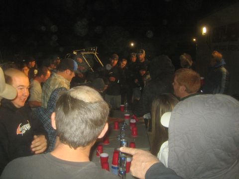 1990 Ford Bronco - People crowd around a folding table lined with red cups at night, with an off-road buggy visible in the background.