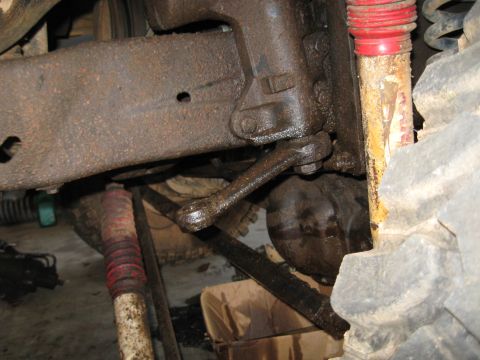 1978 Ford Bronco - Undercarriage view shows heavily greased and rusted steering and suspension parts, including a shock absorber and linkage.