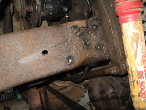 1978 Ford Bronco - This image shows a close-up view of a heavily rusted vehicle frame and suspension parts, with no clear identifying year markers.
