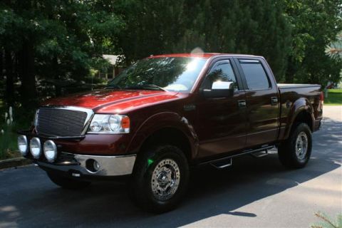 2006 Ford F-150 - A red 2006 Ford F-150 pickup truck is shown from a three-quarter front angle on a sunny day.