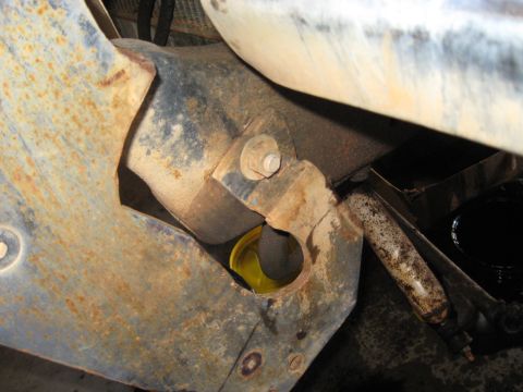 1978 Ford Bronco - A close-up view of a rusty suspension component with a yellow bushing visible.