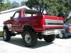 1996 Ford Bronco - Very small, low-resolution thumbnail of a lifted red 1990s Ford Bronco with a white/silver lower two-tone, seen from the driver-side rear t…