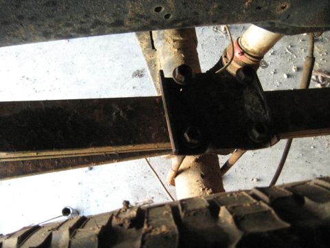 1978 Ford Bronco - Underside view of a vehicle's suspension system, showing a leaf spring and shock absorber attachment.