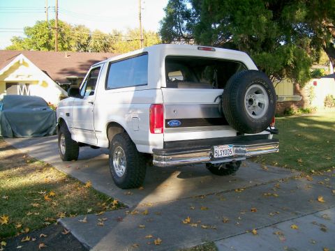 1995 Ford Bronco - This white Ford Bronco is parked in a driveway with a spare tire mounted on the rear door.