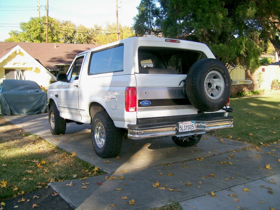 White 1995 Ford Bronco parked in driveway, spare tire on back