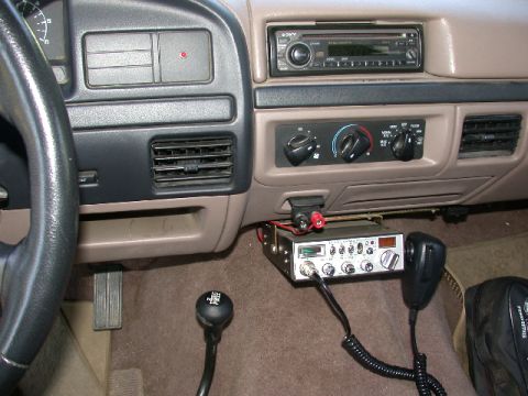 1996 Ford Bronco - Ford truck dashboard with aftermarket Sony head unit, rotary HVAC controls, manual shifter and a mounted CB radio with mic.