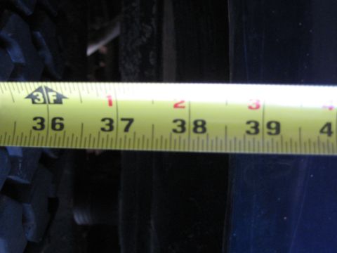 1978 Ford Bronco - A measuring tape is used to measure the clearance of a vehicle's tire and suspension components.